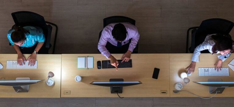 Top view of Asian Male customer care service working hard late in night shift at office,call center department,worker and overtime,team work with colleagues for success